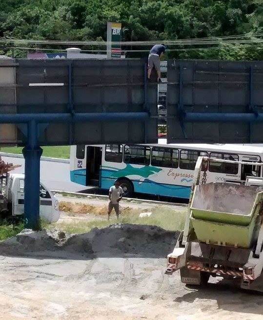 Homem fazendo manutenção de outdoor na Av. do Estado, no bairro Ariribá, também sem nenhum equipamento de segurança. (Crédito: BC da Deprê)