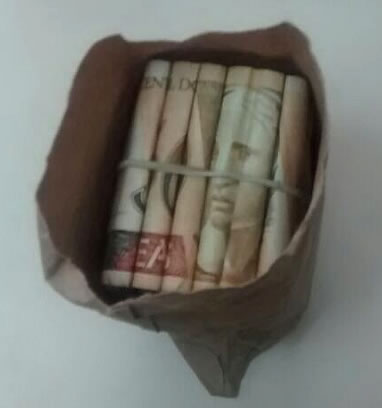 Jovem cai em golpe na fila do banco e perde mais de R$ 3 mil reais 1 Vítima achou que o envelope estava cheio de dinheiro, mas só havia uma nota de 50 reais enrolada em um monte de papéis. (Polícia Militar / Divulgação)