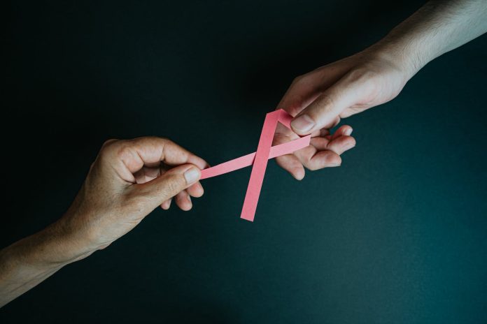 hands holding breast cancer pink paper ribbon